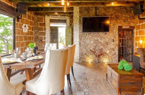 a dining room with a wooden table and a stone wall at Quinta María Victoria in Bernal