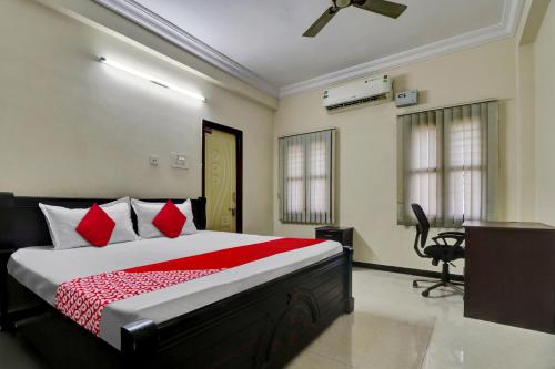 Cette chambre comprend un lit avec des oreillers rouges et un bureau. dans l'établissement OYO Shri Inn, à Vijayawada