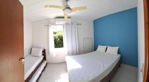 um quarto azul e branco com uma cama e uma janela em VILLAGIO CHARMOSO NA PRAIA DA MOCOCA em Caraguatatuba