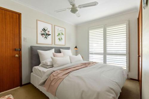een slaapkamer met een groot bed met witte kussens bij Mollymook Fantastic Holiday House in Mollymook