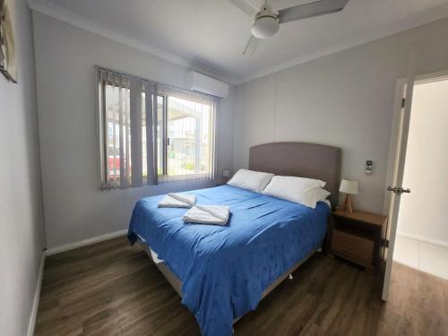 a bedroom with a blue bed and a window at Unit 26 Seafront Estate in Jurien Bay