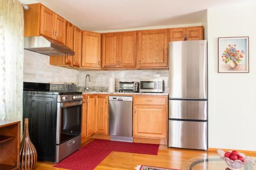 a kitchen with wooden cabinets and a stainless steel refrigerator at Beautiful Apartment-5 Beds-Full Kitchen-Parking-Super Clean! in Boston