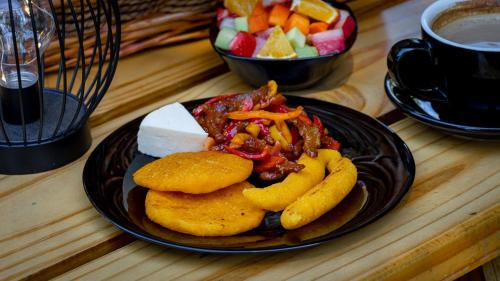 a plate of food on a table with a bowl of fruit at Hotel Boutique Los Abetos in Boquete