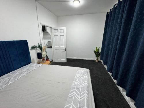 a bedroom with a bed and blue curtains at Flat in Cheam in Sutton