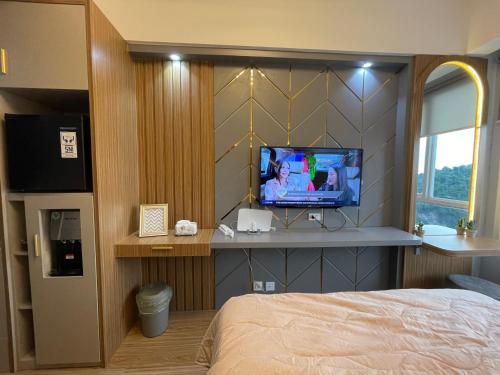 a bedroom with a bed and a tv on a wall at Apart The Bay Lampung in Kuala