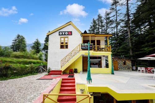 una pequeña casa de color amarillo y blanco en OYO Asha Cottage, en Manali