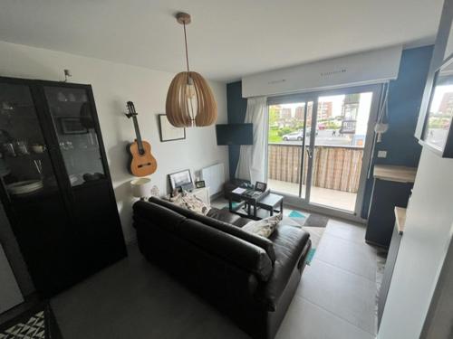 un salon avec un canapé et une guitare dans l'établissement Bel appartement 3 pièces avec WIFI, proche plage et commerces, balcon et parking privé. - FR-1-712-79, à Villers-sur-Mer