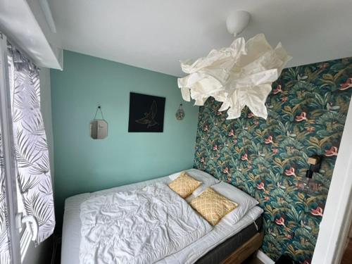 - une petite chambre avec un lit et un mur orné de fleurs dans l'établissement Bel appartement 3 pièces avec WIFI, proche plage et commerces, balcon et parking privé. - FR-1-712-79, à Villers-sur-Mer