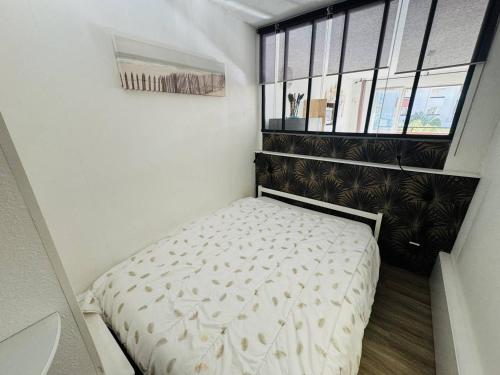 - un petit lit dans une petite chambre avec fenêtre dans l'établissement Appartement rénové près du port avec parking privatif - FR-1-723-156, au Cap d'Agde