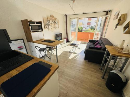 un petit salon avec un canapé et une cuisine dans l'établissement Appartement rénové près du port avec parking privatif - FR-1-723-156, au Cap d'Agde