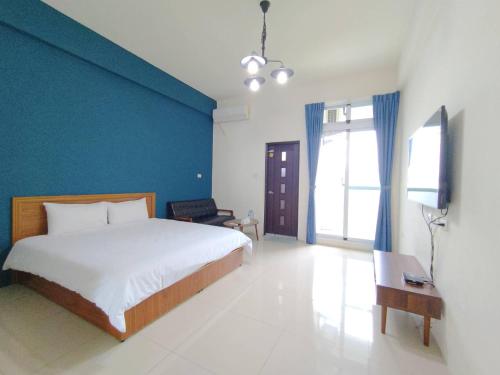 - une chambre avec un lit et un mur bleu dans l'établissement 強國特調民宿, à Taïtung