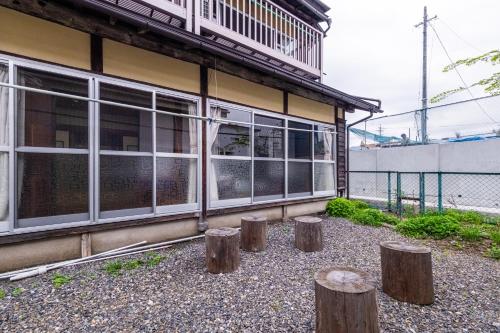 a building with tree stumps in front of it at Hostel みんか松本 in Matsumoto