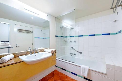 a bathroom with a sink and a shower and a tub at Pool Relaxation on Esplanade across Two Apartments in Darwin