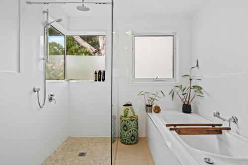 uma casa de banho branca com uma banheira e um chuveiro em Sea views at Spring Beach Tasmanias East Coast em Spring Beach
