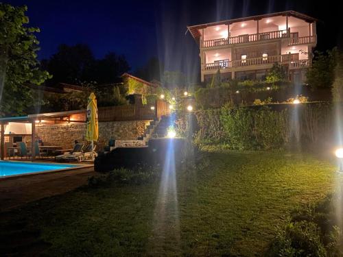 Вила Алекс في Razvalatsi: منزل به نافورة أمام المسبح ليلاً