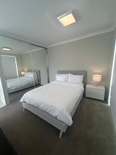 a bedroom with a large white bed and a mirror at Apartment close to the beach in Jindalee