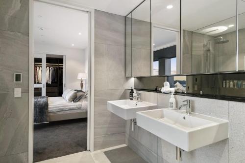 Wynyard Quarter Apartments by Urban Rest في أوكلاند: حمام مع مغسلتين وغرفة نوم