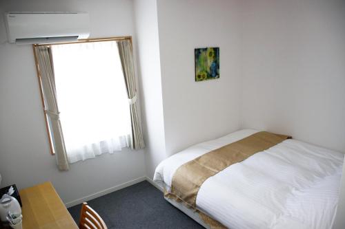 Habitación pequeña con cama y ventana en ビジネスホテル 山手INN en Iidamachi