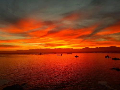 a sunset on a lake with boats in the water at Costa del mar in Quintero