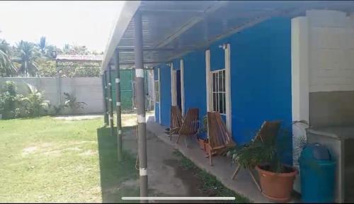 une maison bleue avec des chaises sur la terrasse couverte dans l'établissement Rancho la potranca sv, 