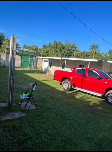 un camion rouge garé dans une cour avec une chaise dans l'établissement Rancho la potranca sv, 
