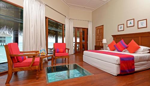 a bedroom with a bed and a table and chairs at Adaaran Club Rannalhi - All Inclusive in South Male Atoll