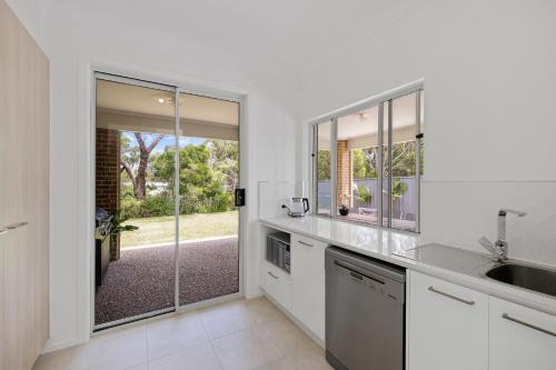 a kitchen with a sink and a sliding glass door at Cowes Family Beach House in Cowes