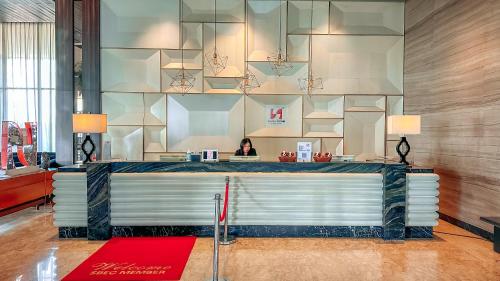 a woman sitting at a counter in a lobby at Swiss-Belinn Karawang in Karawang