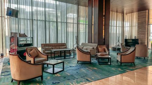 a lobby with chairs and tables and windows at Swiss-Belinn Karawang in Karawang