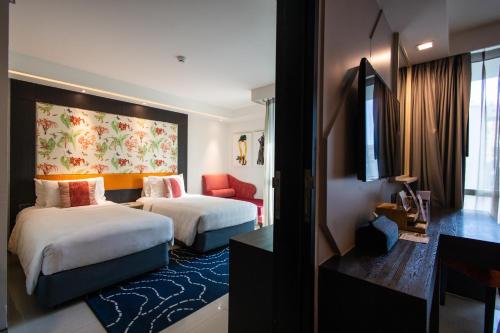 a hotel room with two beds and a tv at Hotel Clover Asoke - SHA Extra Plus in Bangkok