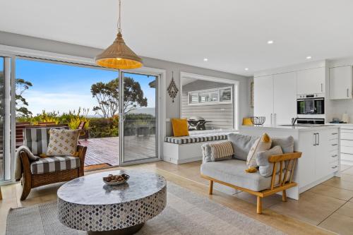 a living room with a table and a kitchen at Sea views at Spring Beach Tasmanias East Coast in Spring Beach