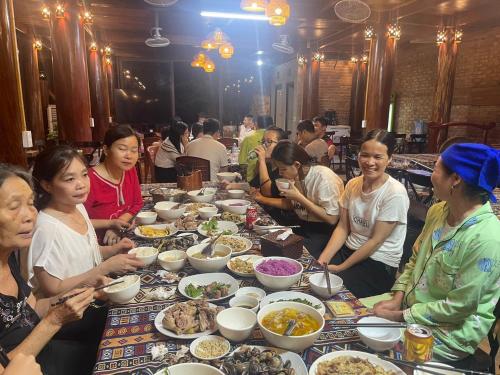a group of people sitting at a table eating food at Pù Luông Sala Homestay in Hương Bá Thước