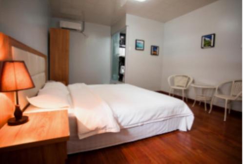 um quarto com uma cama branca, uma mesa e cadeiras em Pacific Islander Inn em Garapan