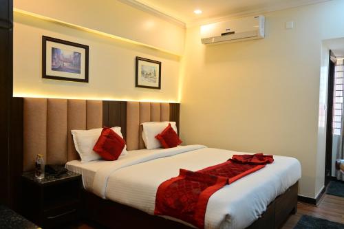 um quarto com uma cama grande e almofadas vermelhas em Hotel Golden Riviera em Mysore
