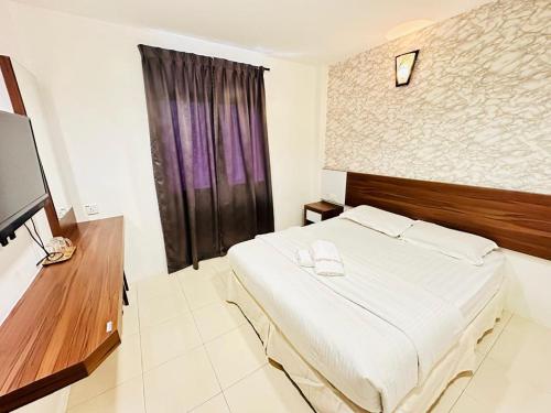 um quarto com uma cama grande e uma televisão em Rainbow Hotel em Alor Setar