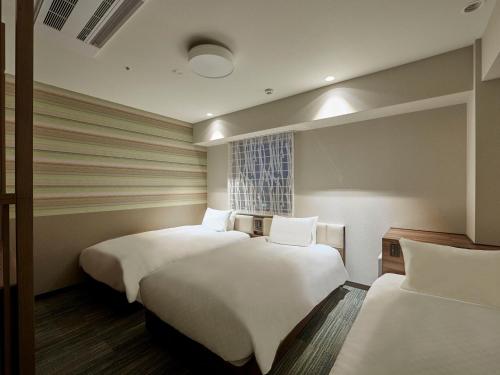a hotel room with two beds and a window at Hearton Hotel Shinsaibashi Nagahoridouri in Osaka