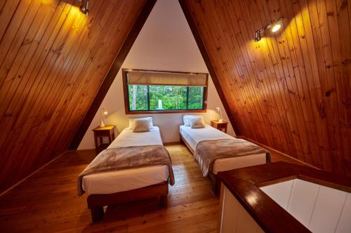 a attic room with two beds and a window at Rose Gums Wilderness Retreat in Butchers Creek