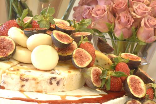 a cake with fruit on top of it next to a vase of roses at Mont d'Or Monte Bello Estate in Bloemfontein