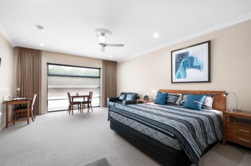 a bedroom with a bed and a table and chairs at Bridges on Argyle in Traralgon