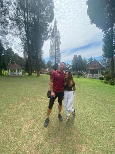 a man and woman posing for a picture in a field at Sibayak Multinational Rest House in Berastagi
