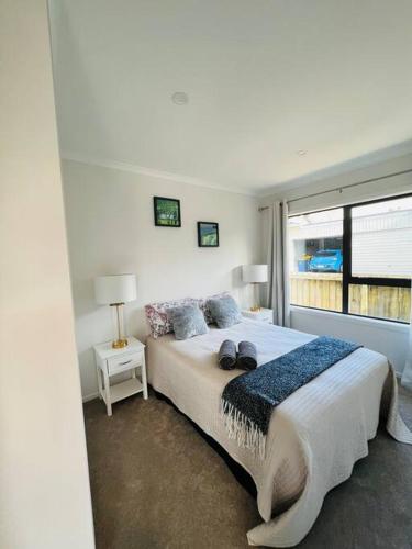 a white bedroom with a large bed and a window at Matuhi Deluxe 2 bedrooms unit in Auckland