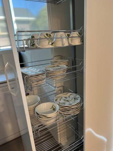 a refrigerator filled with white plates and dishes at Matuhi Deluxe 2 bedrooms unit in Auckland