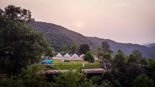 un groupe de tentes dans un champ avec une montagne dans l'établissement Khu du lịch sinh thái Cỏ Lau Village, à Làng Song Ca
