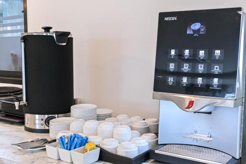 a coffee machine with cups and plates on a counter at Shewin de Bangkok in Ban Bang Bamru