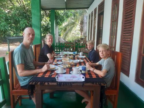 a family sitting at a table with a chessboard at Jm Resort in Dambulla