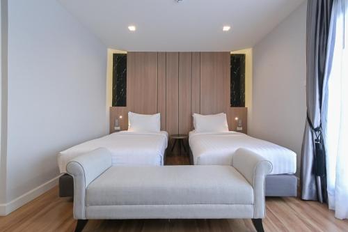 two beds and a couch in a room with windows at Shewin de Bangkok in Ban Bang Bamru