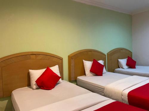 two beds with red pillows in a room at HOTEL SAHARA INN BATU CAVES in Batu Caves