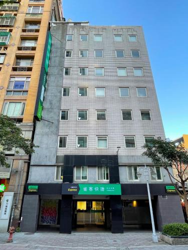 a tall gray building with a green sign on it at CHECK inn Express Taipei Yongkang in Taipei