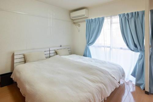 a bedroom with a white bed and a window at Westeria202 JR春日井駅徒歩3分ペット連れ長期滞在可能 in Kasugai
