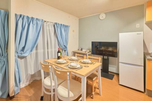 a kitchen with a table with chairs and a refrigerator at Westeria202 JR春日井駅徒歩3分ペット連れ長期滞在可能 in Kasugai